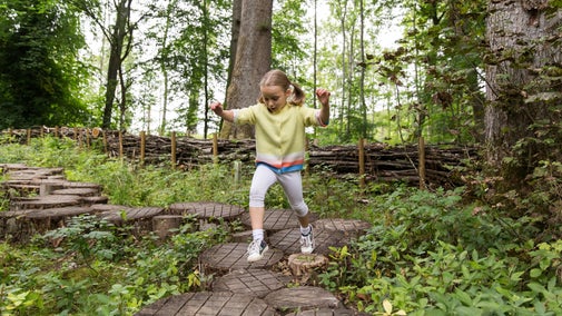 Girl playing in the Little Acorns nature play space at Wallington, Northumberland